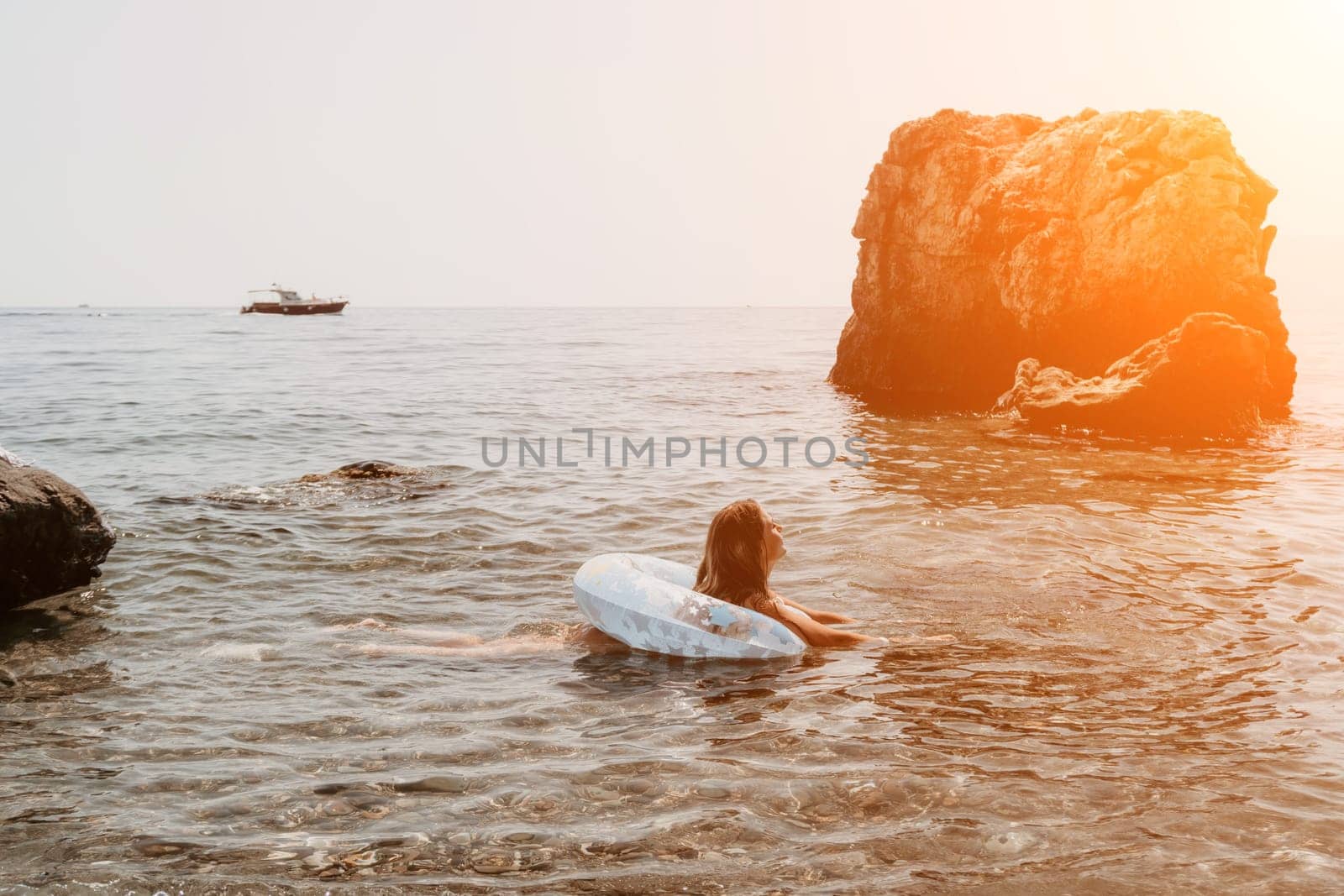 Woman summer sea. Happy woman swimming with inflatable donut on the beach in summer sunny day, surrounded by volcanic mountains. Summer vacation concept