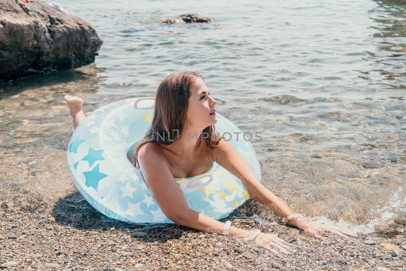 Woman summer sea. Happy woman swimming with inflatable donut on the beach in summer sunny day, surrounded by volcanic mountains. Summer vacation concept