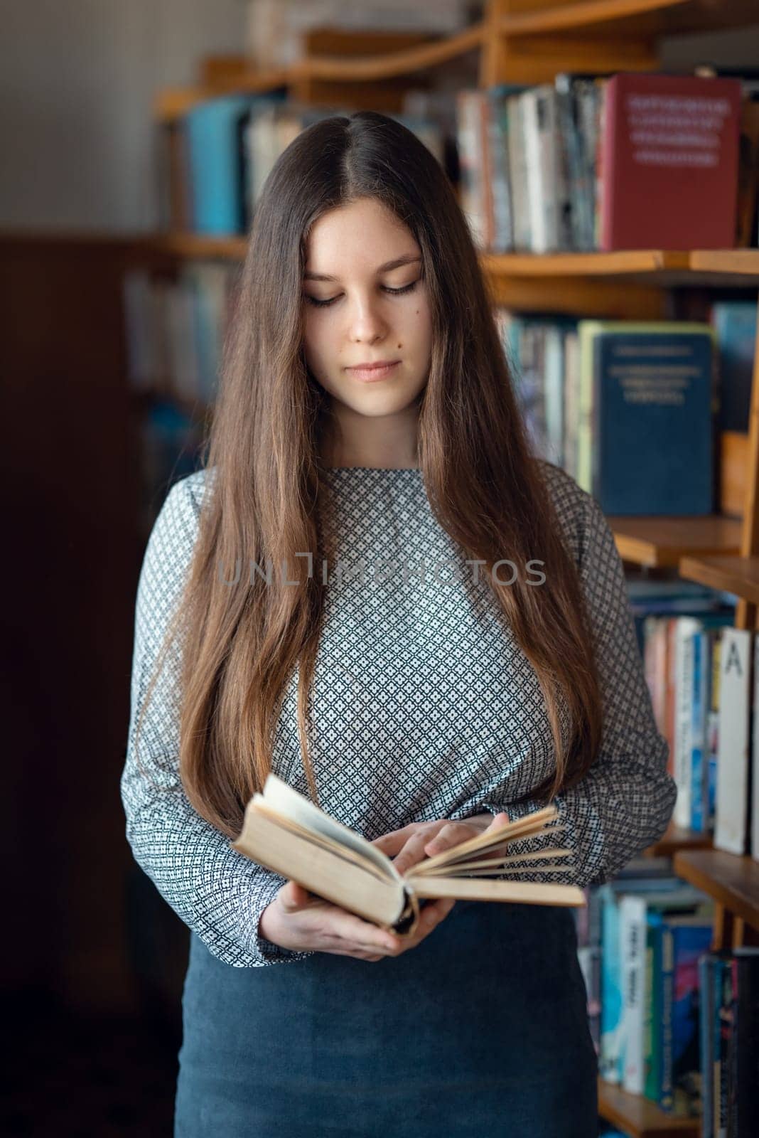 Young girl looking through a book in university library