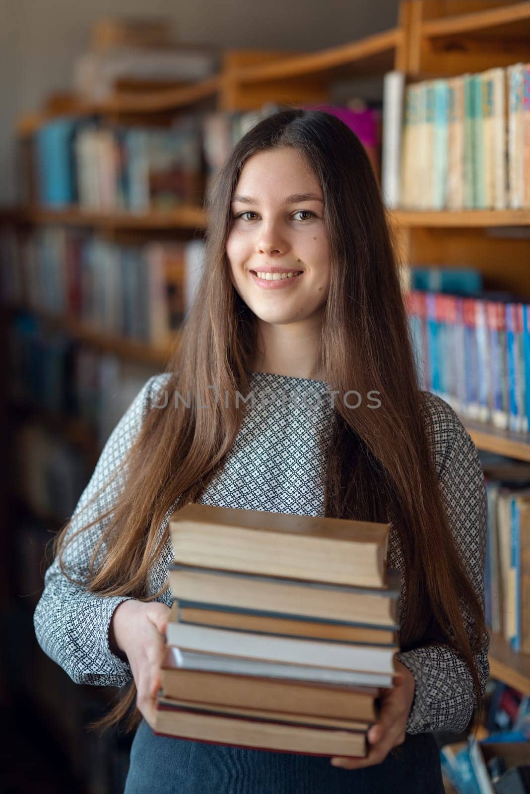 Portrait of a girl student in library with stack of books by VitaliiPetrushenko