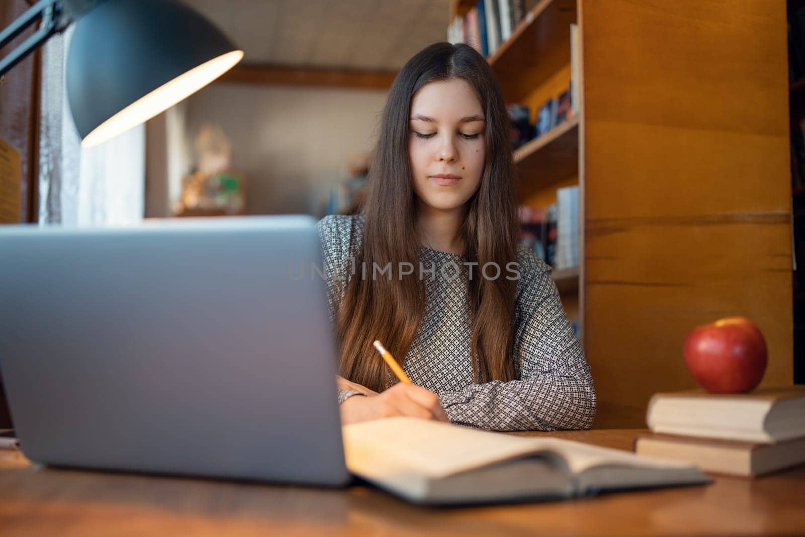 Portrait of a young girl working in university library, getting ready for next classes, reading literature