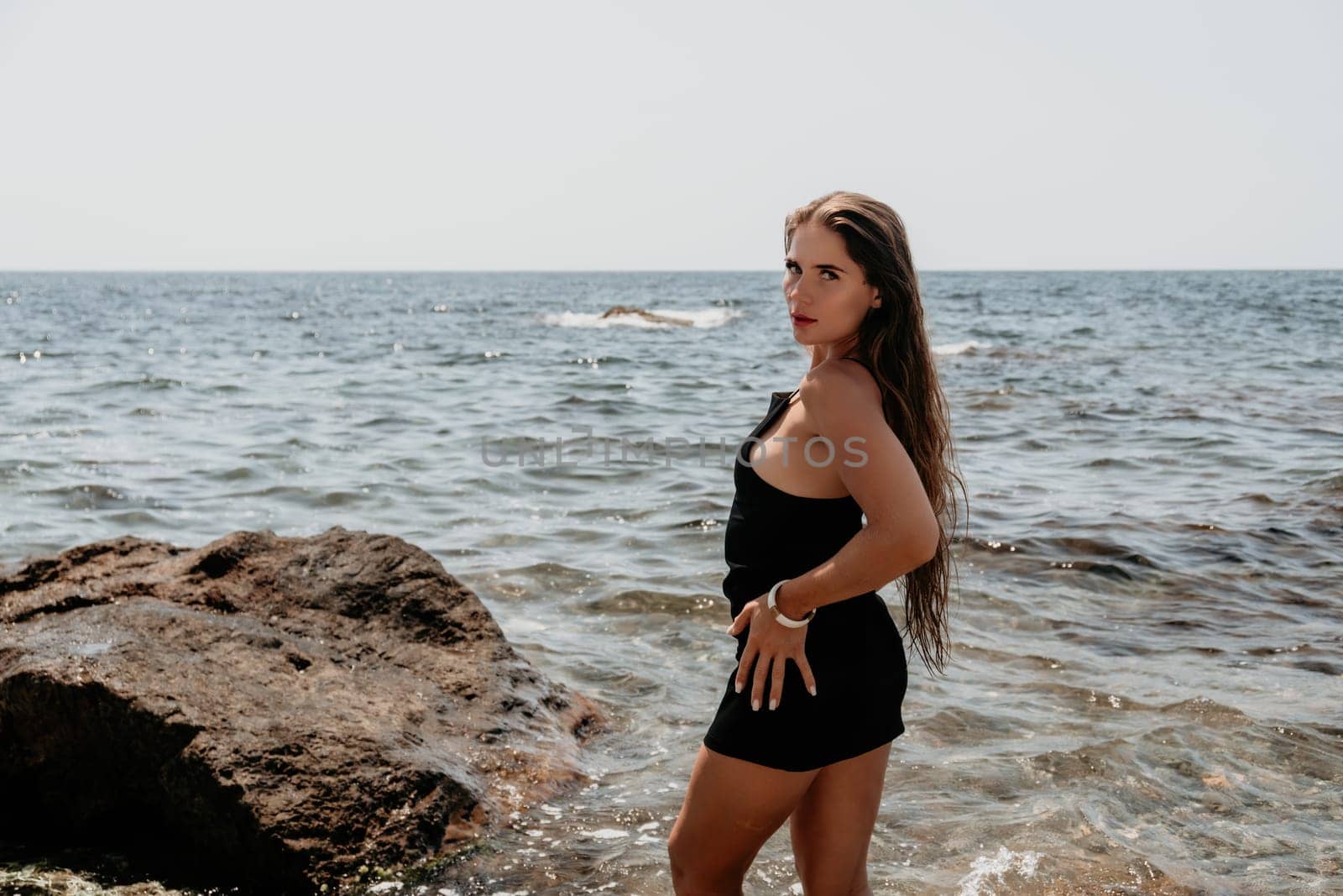 Woman summer travel sea. Happy tourist in hat enjoy taking picture outdoors for memories. Woman traveler posing on the beach at sea surrounded by volcanic mountains, sharing travel adventure journey by panophotograph