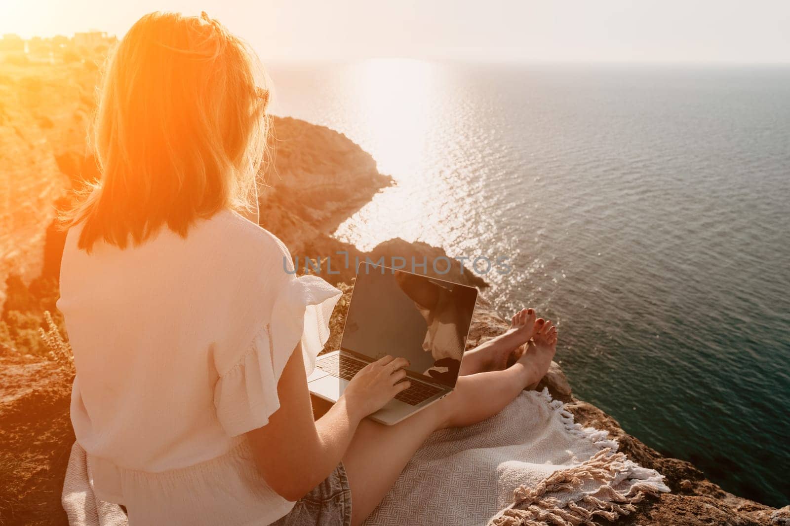 Woman sea laptop. Business woman in yellow hat working on laptop by sea. Close up on hands of pretty lady typing on computer outdoors summer day. Freelance, digital nomad, travel and holidays concept.