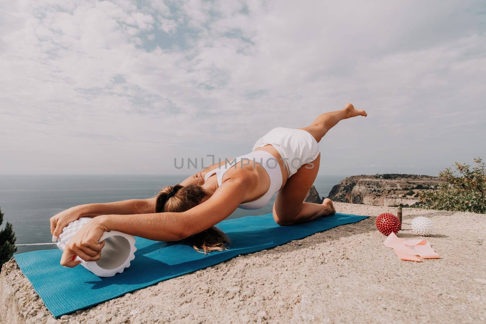 Woman sea pilates. Sporty, middle-aged woman practicing pilates in park near the sea. trains on a yoga mat and exudes a happy and active demeanor. healthy lifestyle through exercise and meditation. by panophotograph