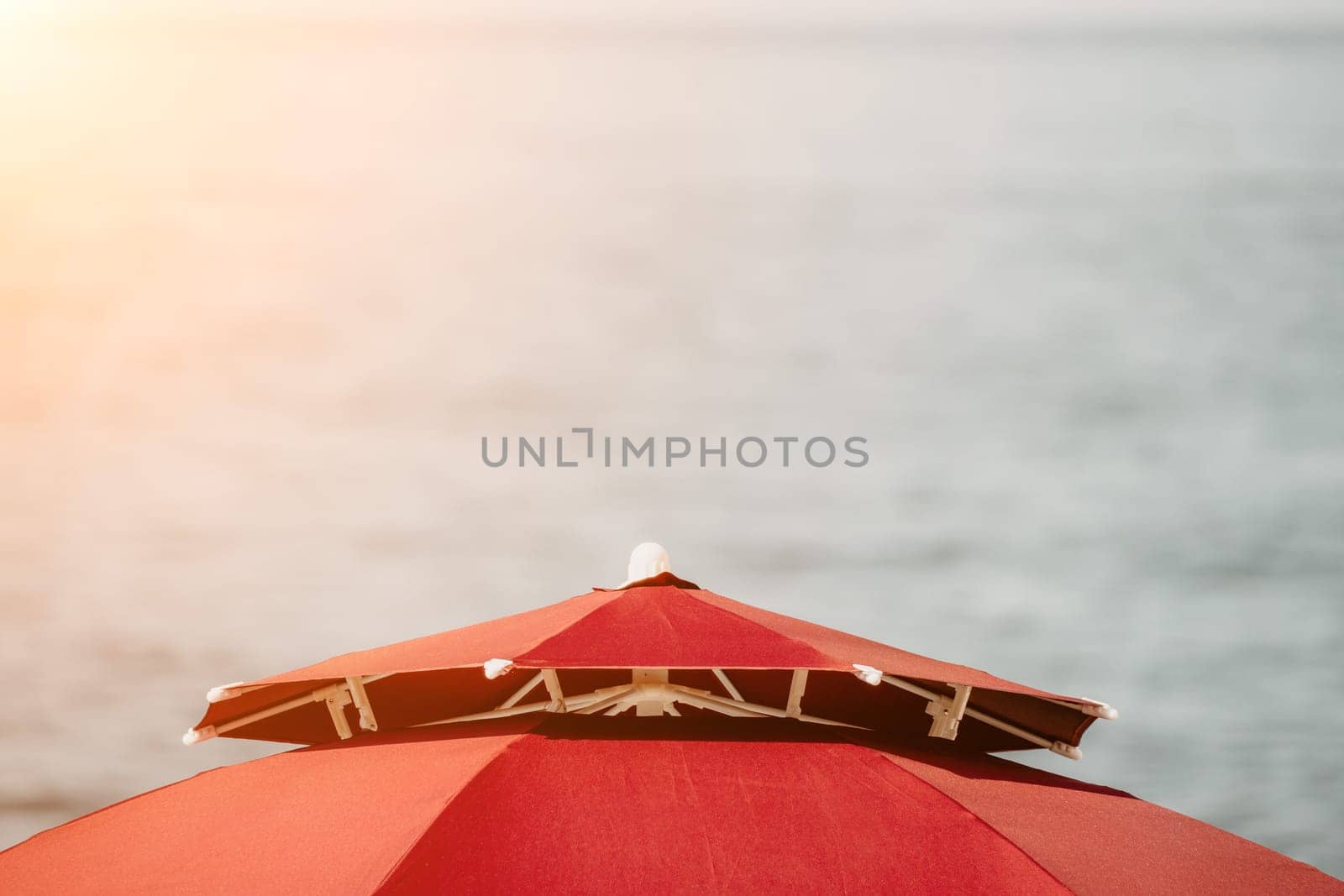 Red Beach Umbrella on the Background of the Blue Sea Ocean. Beach Landscape. Summer travel and holidays concept