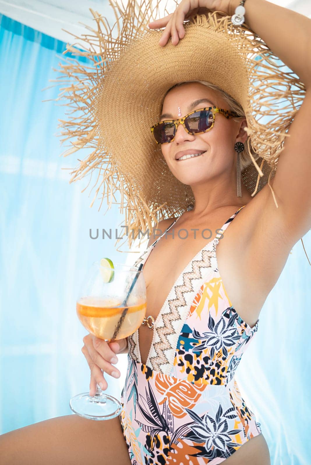 sexy young girl in a straw hat on vacation drinks a cocktail, smiles, gets high and enjoys life in the summer by Rotozey