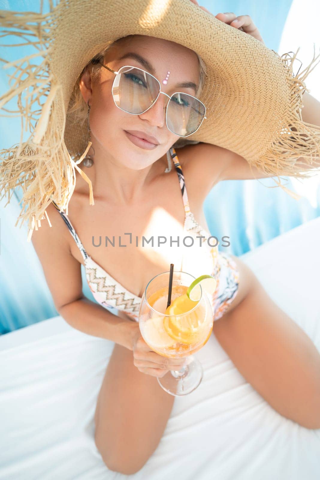 sexy young girl in a straw hat on vacation drinks a cocktail, smiles, gets high and enjoys life in the summer by Rotozey