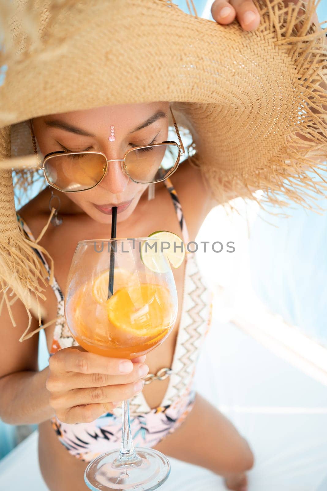 sexy young girl in a straw hat on vacation drinks a cocktail, smiles, gets high and enjoys life in the summer