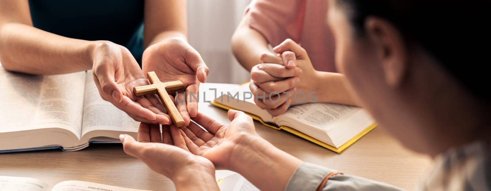 Close-up women prayer deliver holy bible book and holy cross to believer group. Spreading religion symbol. Concept of hope, religion, christianity and god blessing. Warm background. Burgeoning.