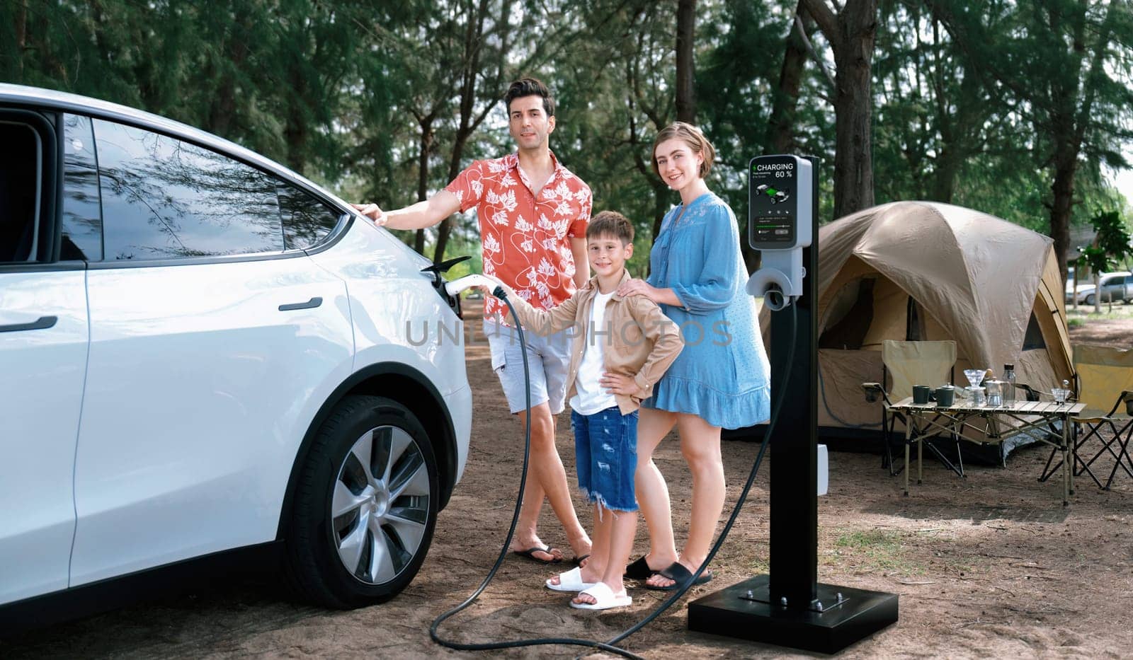 Outdoor adventure and family vacation camping in nature travel by eco friendly car for sustainable future. Lovely family recharge EV car with EV charging station in campsite. Perpetual