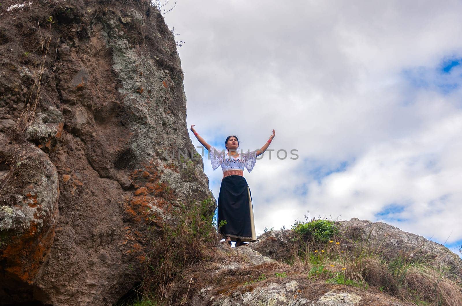 copyspace of panoramic landscape of ecuador with two big rocks where an indian woman imbues mother nature under the white clouds. earth day by Raulmartin