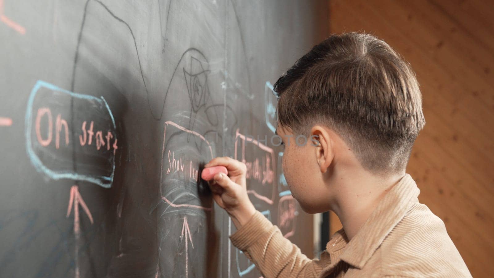 Panorama shot of smart boy writing engineering prompt on blackboard. Attractive student planing a project by using coding and programing system in STEM technology innovative class. Closeup. Erudition.