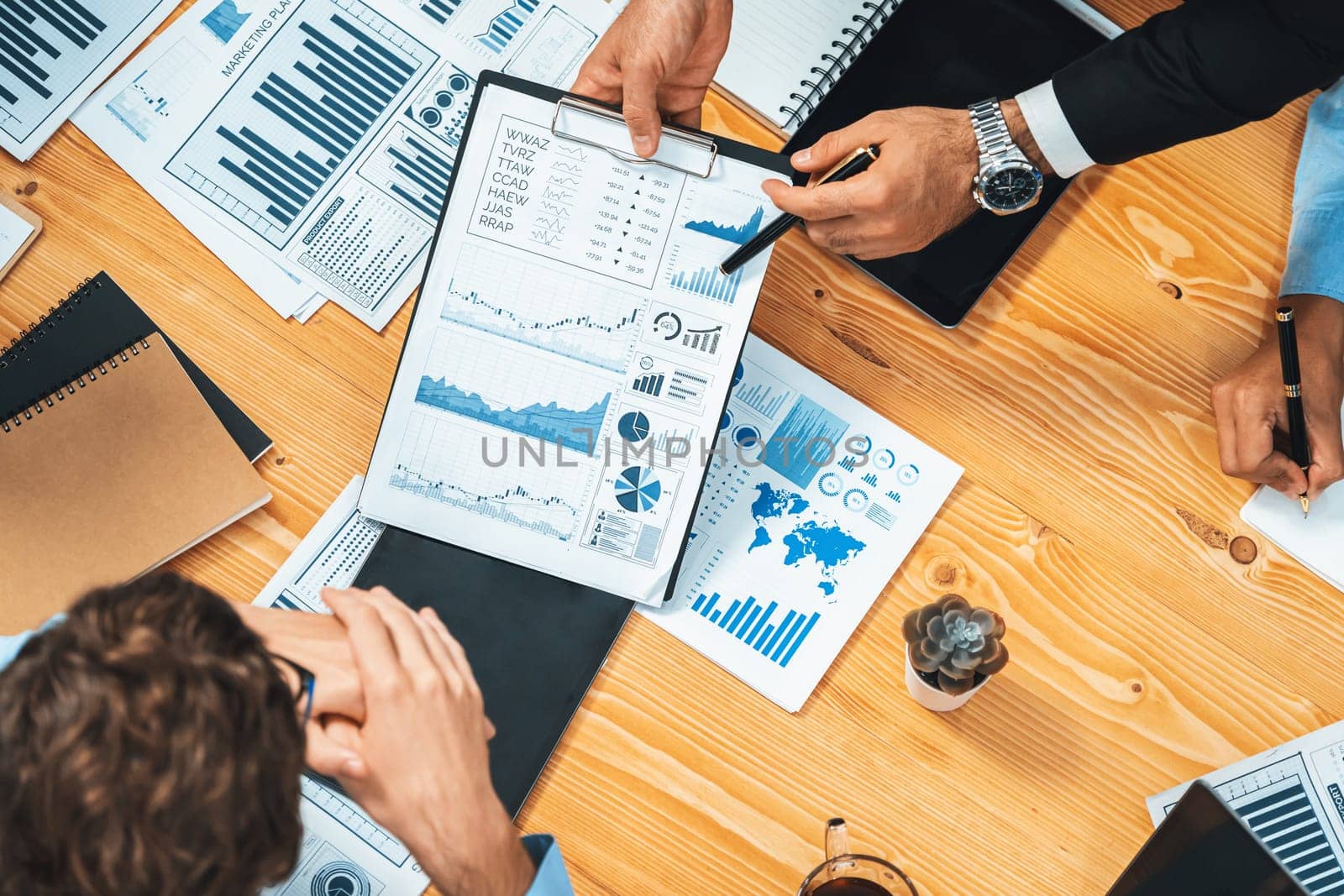 Top view diverse group of business analyst team analyzing financial data report paper on meeting table. Chart and graph dashboard by business intelligence analysis. Meticulous