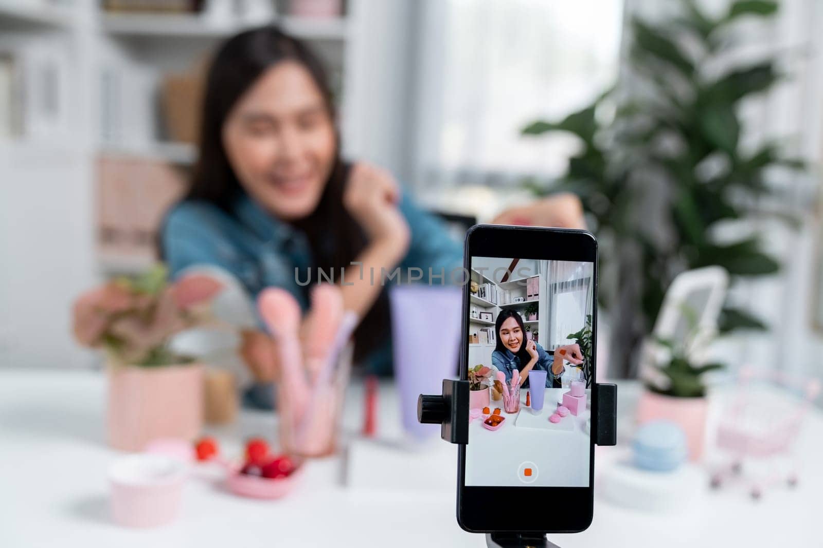 Selective focus phone with young beautiful Asian showing cosmetic makeup lipstick matte pastel color testing bestseller collection on arm test promotion on social media online recording. Stratagem.