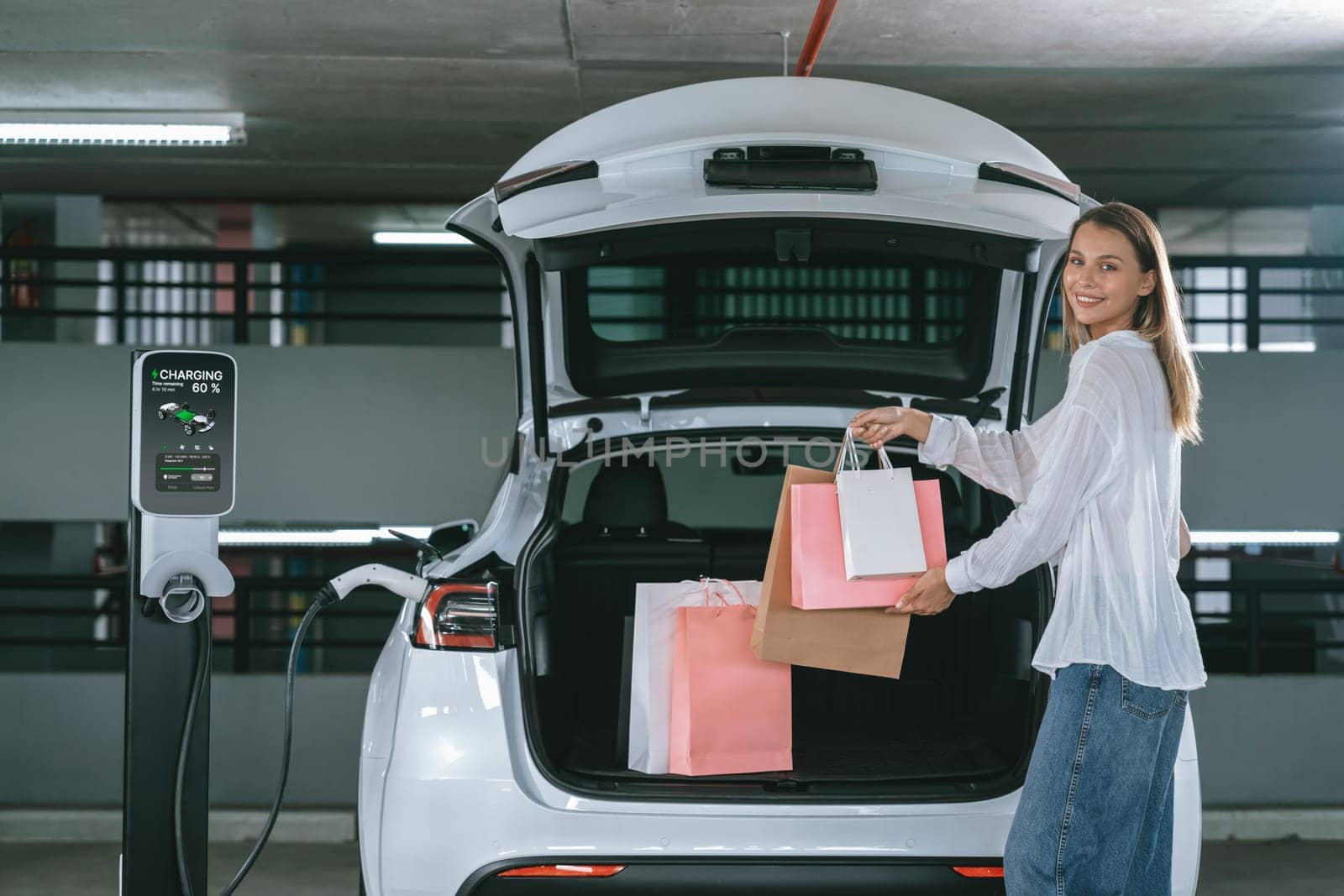 Young woman travel with EV electric car to shopping center parking lot innards by biancoblue