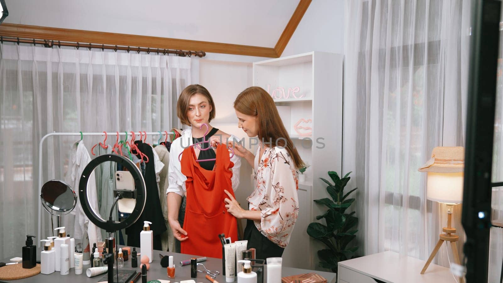 Two women influencer shoot live streaming vlog video review clothes prim social media or blog. Happy young girl with apparel studio lighting for marketing recording session broadcasting online.