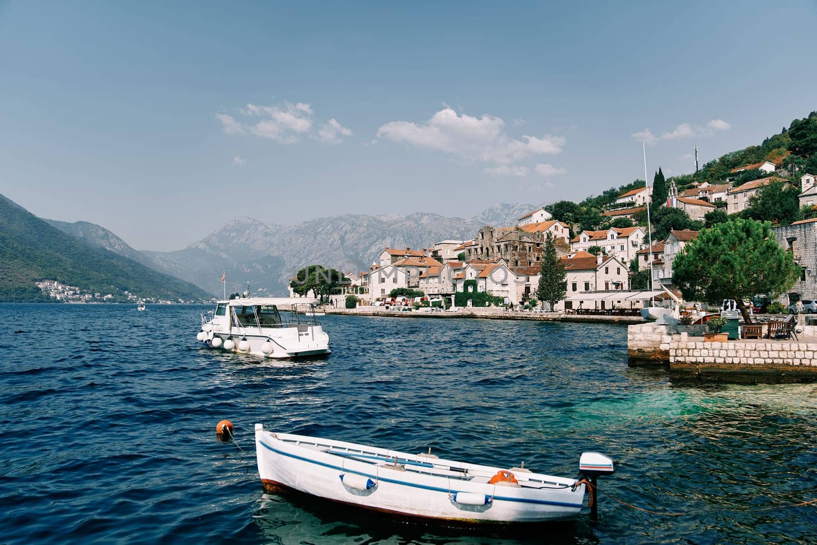 White fishing boat is moored at a pier near the shore of Perast. Montenegro. High quality photo