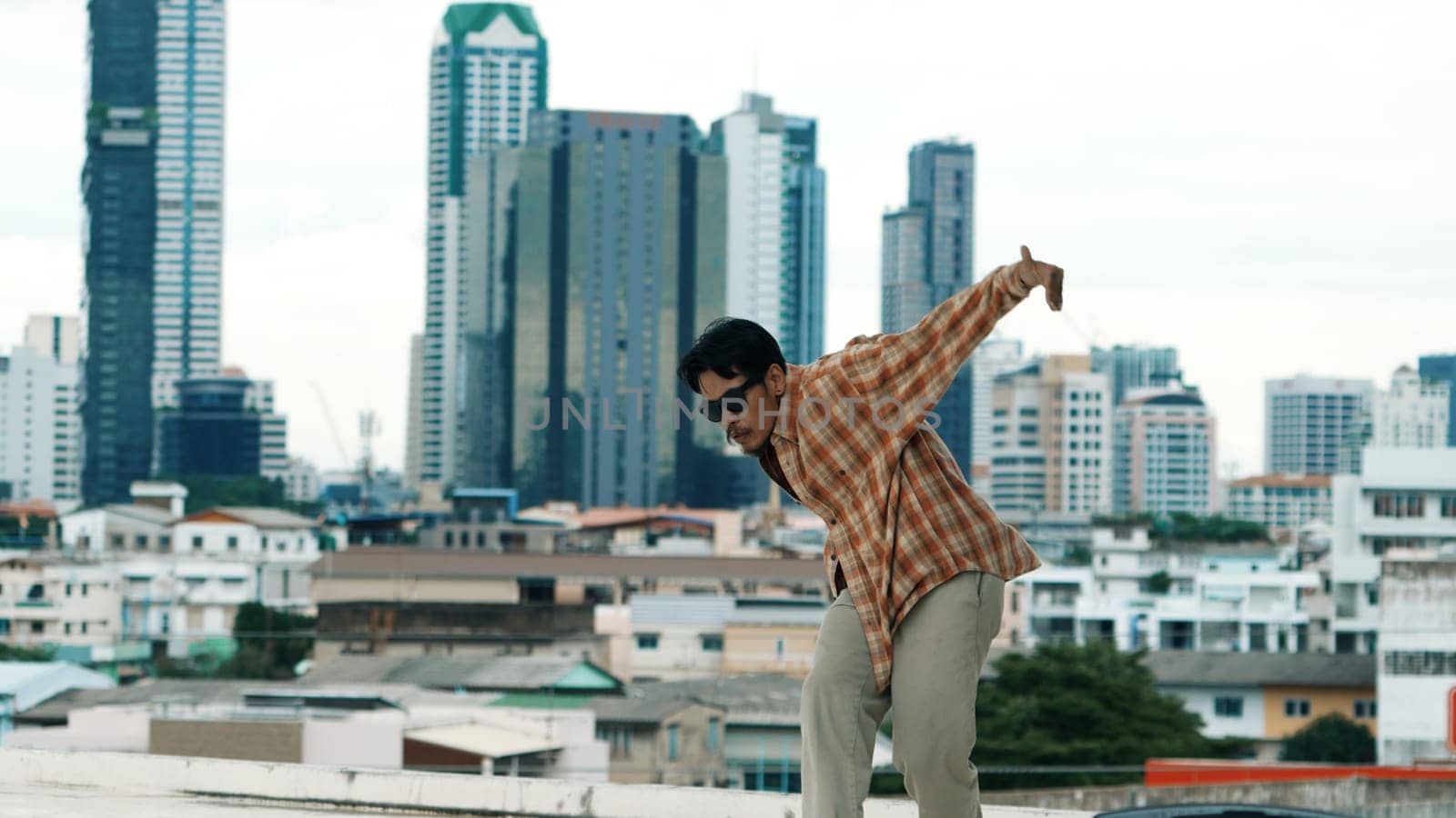 Hispanic break dancer practice B-boy footsteps at roof top with urban city view or sky scrapper. Young modern dancing group doing hip hop movement. Style,fashion,action. Outdoor sport 2024. Endeavor.