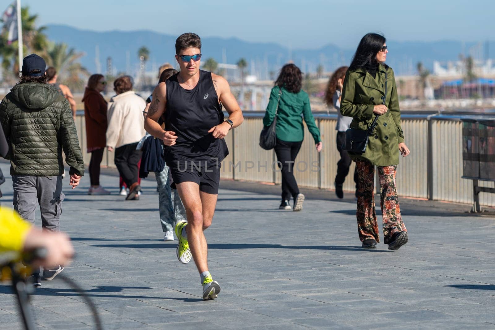 People walk along Barceloneta beach on a sunny day in winter in Barcelona, Catalonia in Spain in winter 2023. by martinscphoto