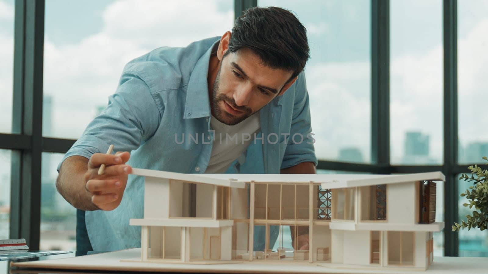 Smart civil architect engineer looking while planing design house construction with blueprint, house model and architectural equipment. Designer measuring and inspecting house model. Tracery