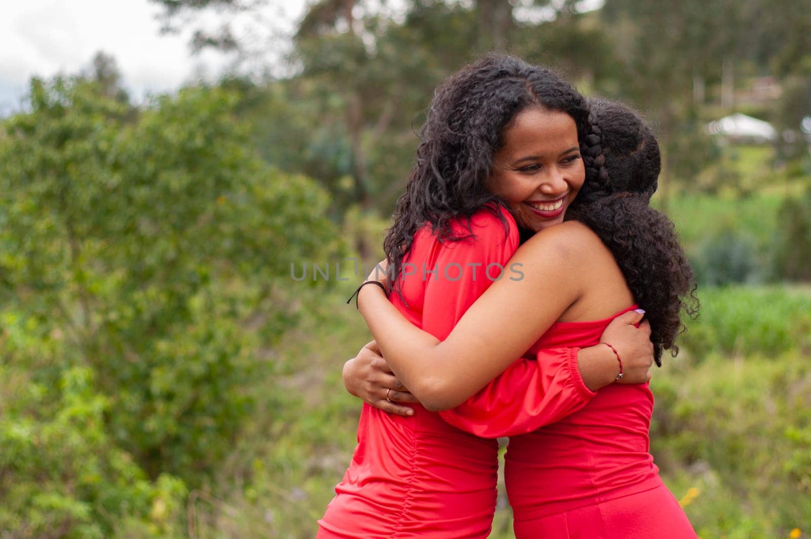 copyspace of a latina girl hugging her friend very excited and happy on the mountain. sincere smile. hug day. by Raulmartin