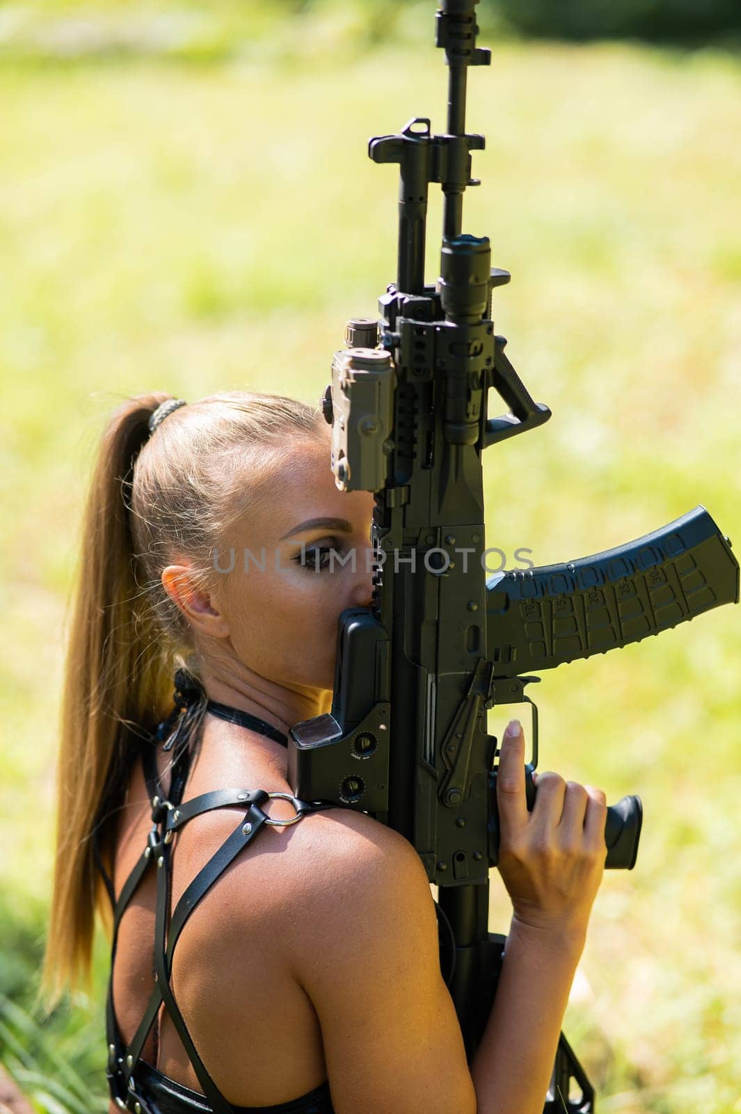Portrait of caucasian woman in bikini sitting with machine gun outdoors