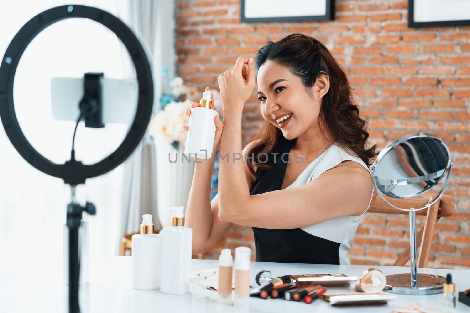 Asian Woman influencer shoot live streaming vlog video review makeup uttermost social media or blog. Happy young girl with cosmetics studio lighting for marketing recording session broadcasting online