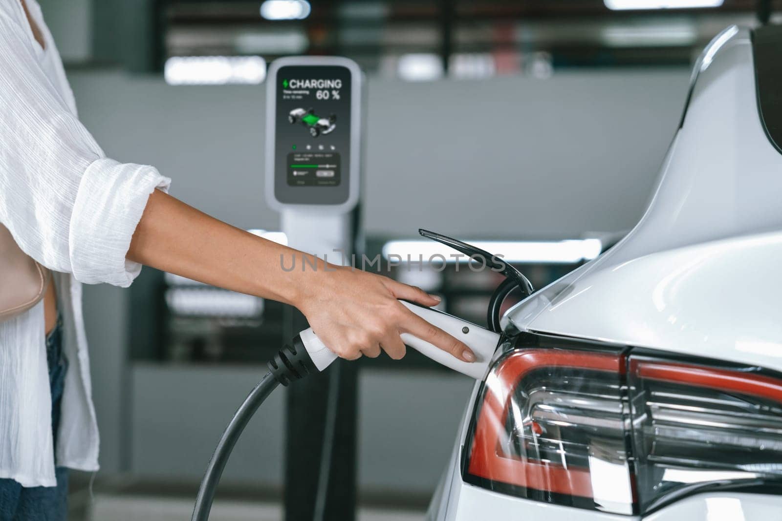 Young woman travel with EV electric car to shopping center parking lot innards by biancoblue