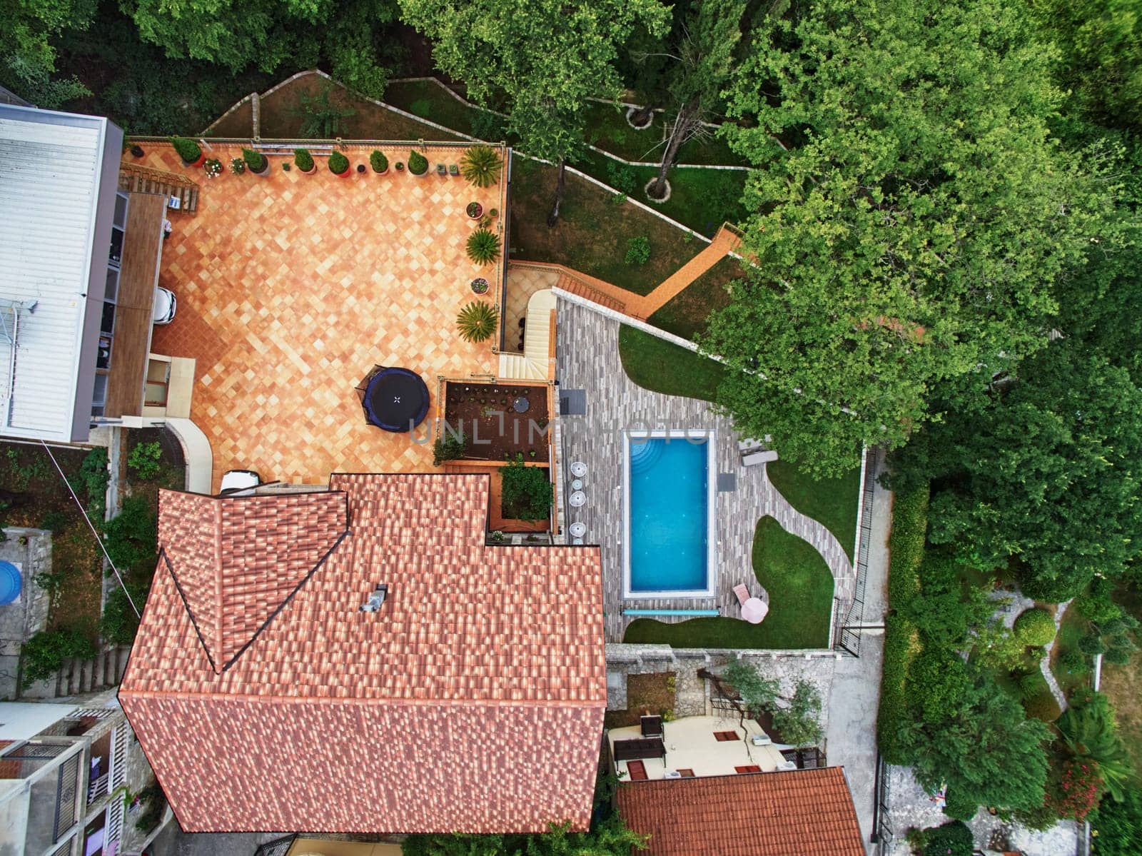 Terrace and swimming pool in the courtyard of a cozy villa among green trees. Drone. High quality photo