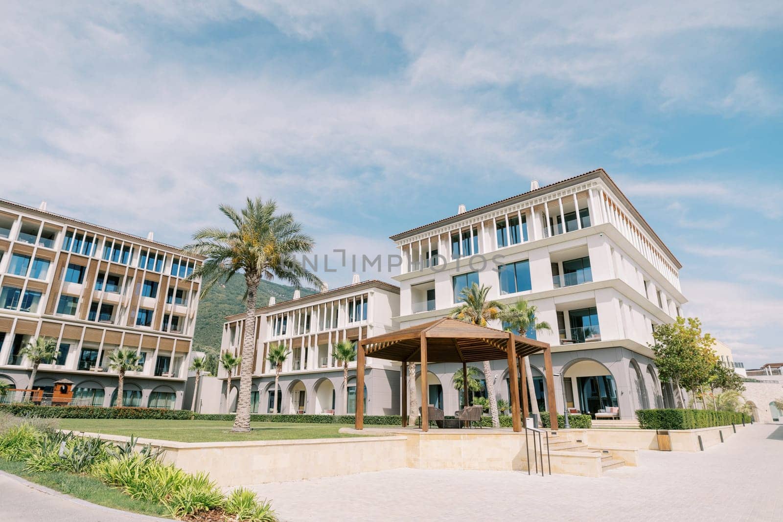 Wooden gazebo with chairs in the courtyard near a modern multi-storey hotel. One and Only, Portonovi, Montenegro. High quality photo