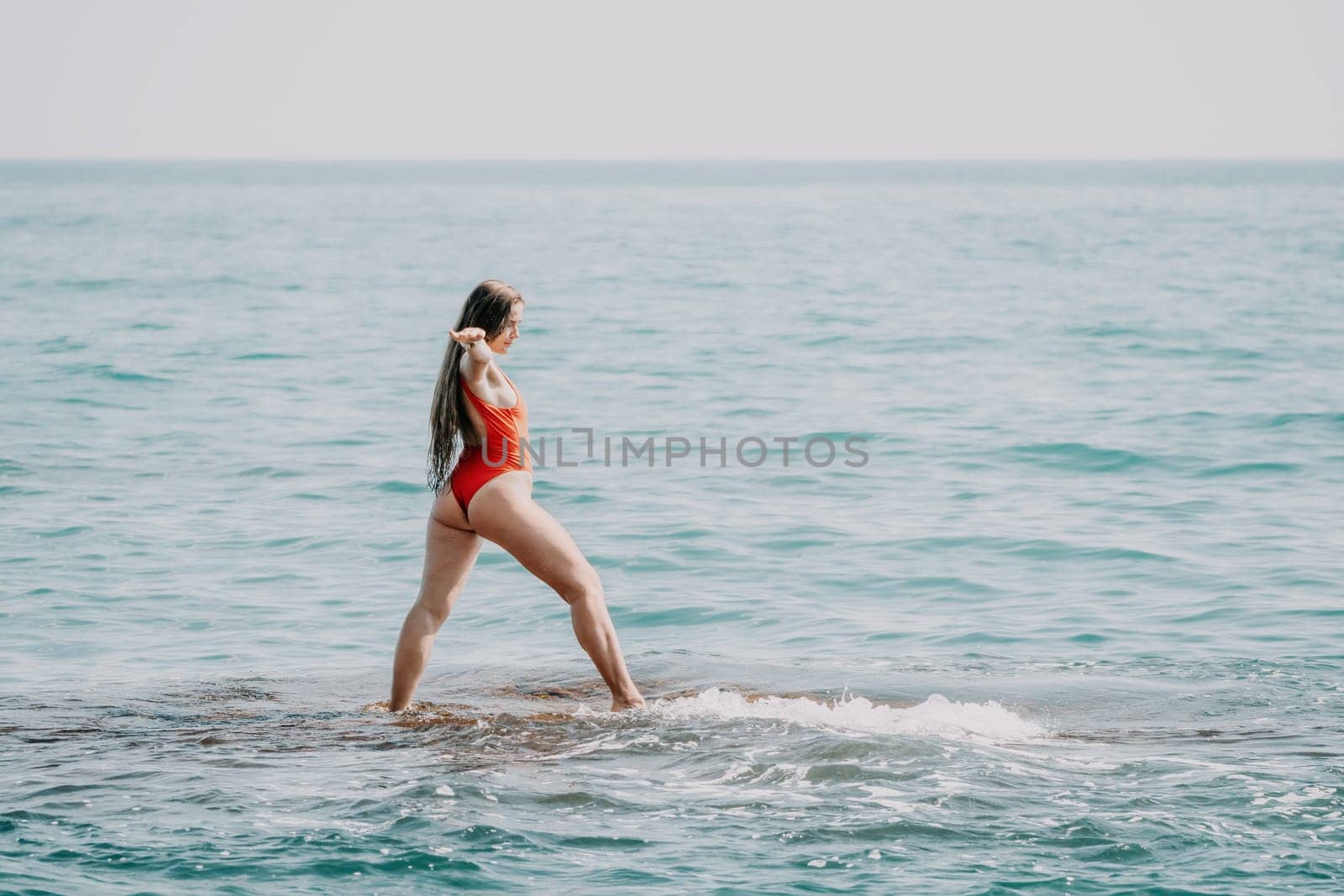 Woman sea yoga. Back view of free calm happy satisfied woman with long hair standing on top rock with yoga position against of sky by the sea. Healthy lifestyle outdoors in nature, fitness concept.