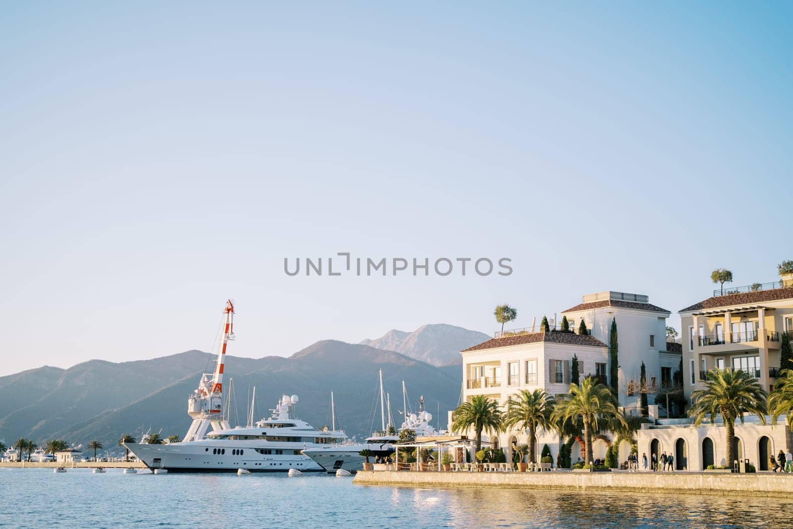 Striped harbor crane stands near moored yachts off the coast of Porto. Montenegro. High quality photo