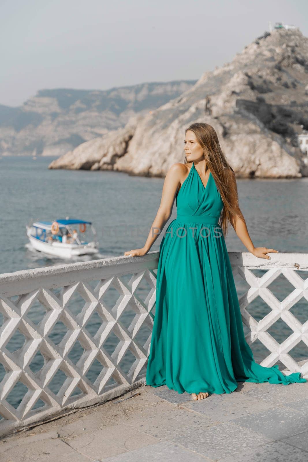 Woman sea trevel green dress. Side view a happy woman with long hair in a long mint dress posing on a beach with calm sea bokeh lights on sunny day. Girl on the nature on blue sky background