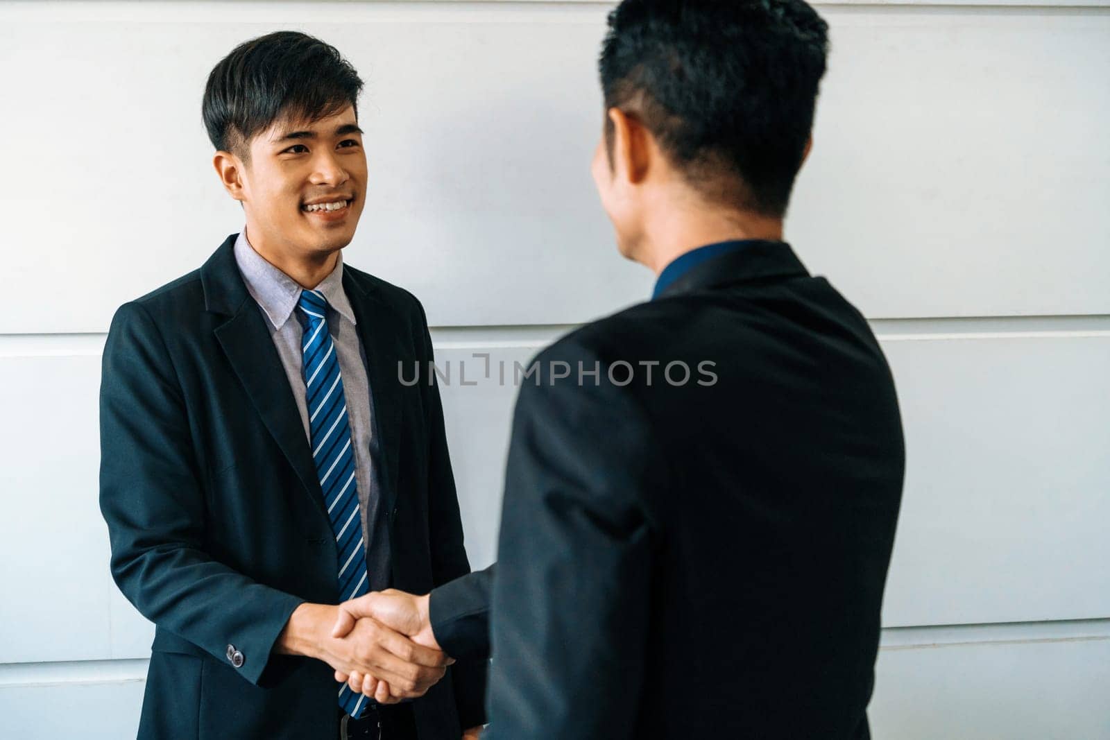 Business people agreement concept. Asian Businessman do handshake with another businessman in the office meeting room. uds