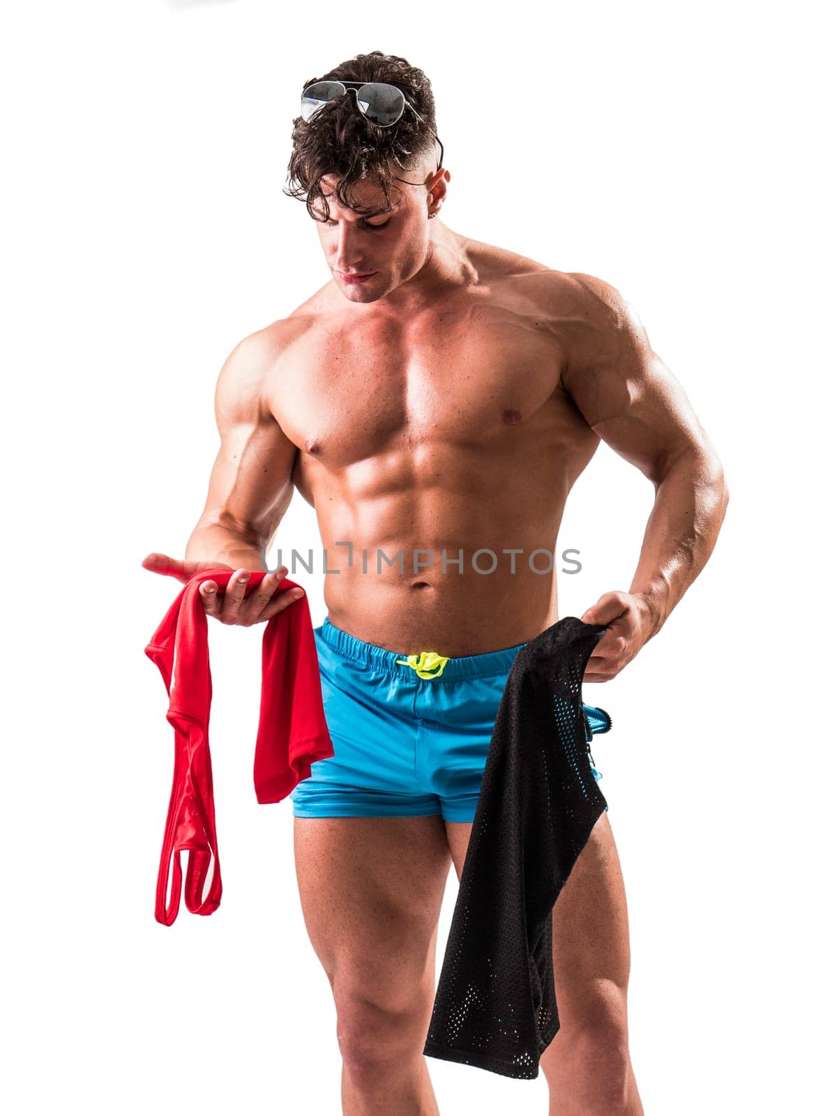Good Looking Young Gym Fit Man Showing His Sexy Six Pack Abs While Looking at Clothes and Garments. Isolated on White Background in Studio