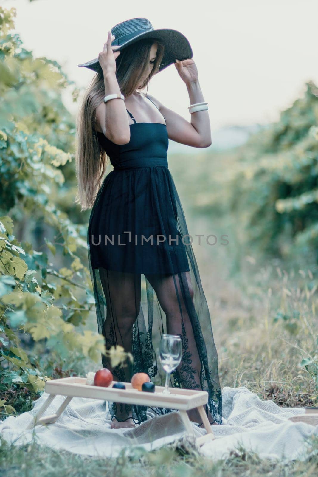 Woman at autumn winery. Portrait of happy woman holding glass of wine and enjoying in vineyard. Elegant young lady in hat toasting with wineglass smiling cheerfully enjoying her stay at vineyard