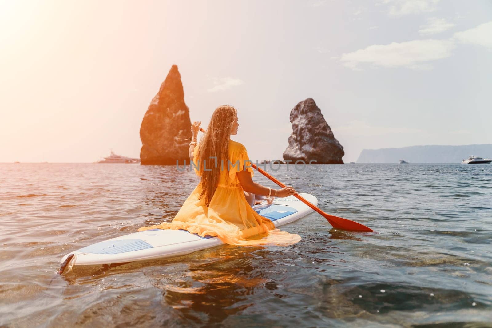 Woman sea sup. Close up portrait of happy young caucasian woman with long hair looking at camera and smiling. Cute woman portrait in bikini posing on sup board in the sea by panophotograph