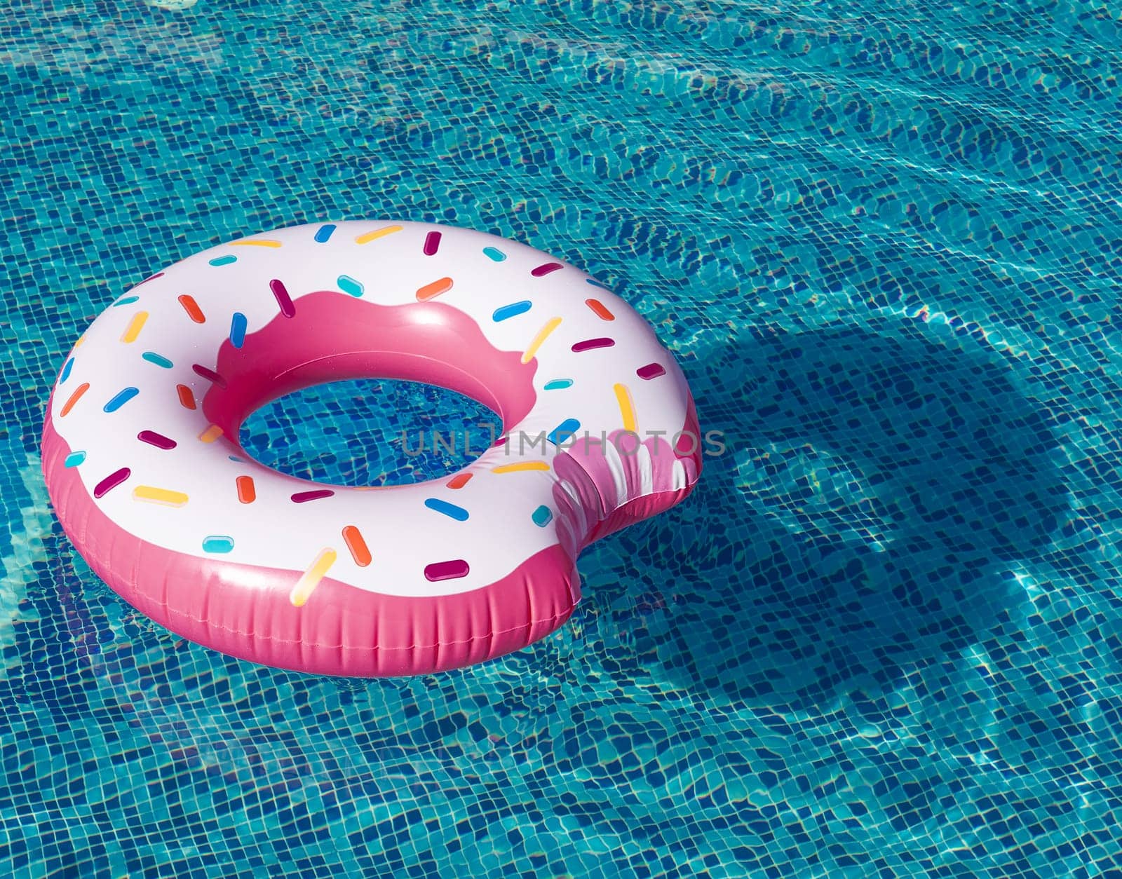 Whimsical inflatable ring, fashioned after a doughnut, rests atop the serene swimming pool