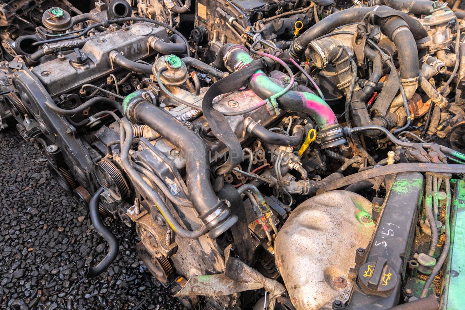 many used internal combustion engines with gearboxes on the ground of junkyard at cloudy day