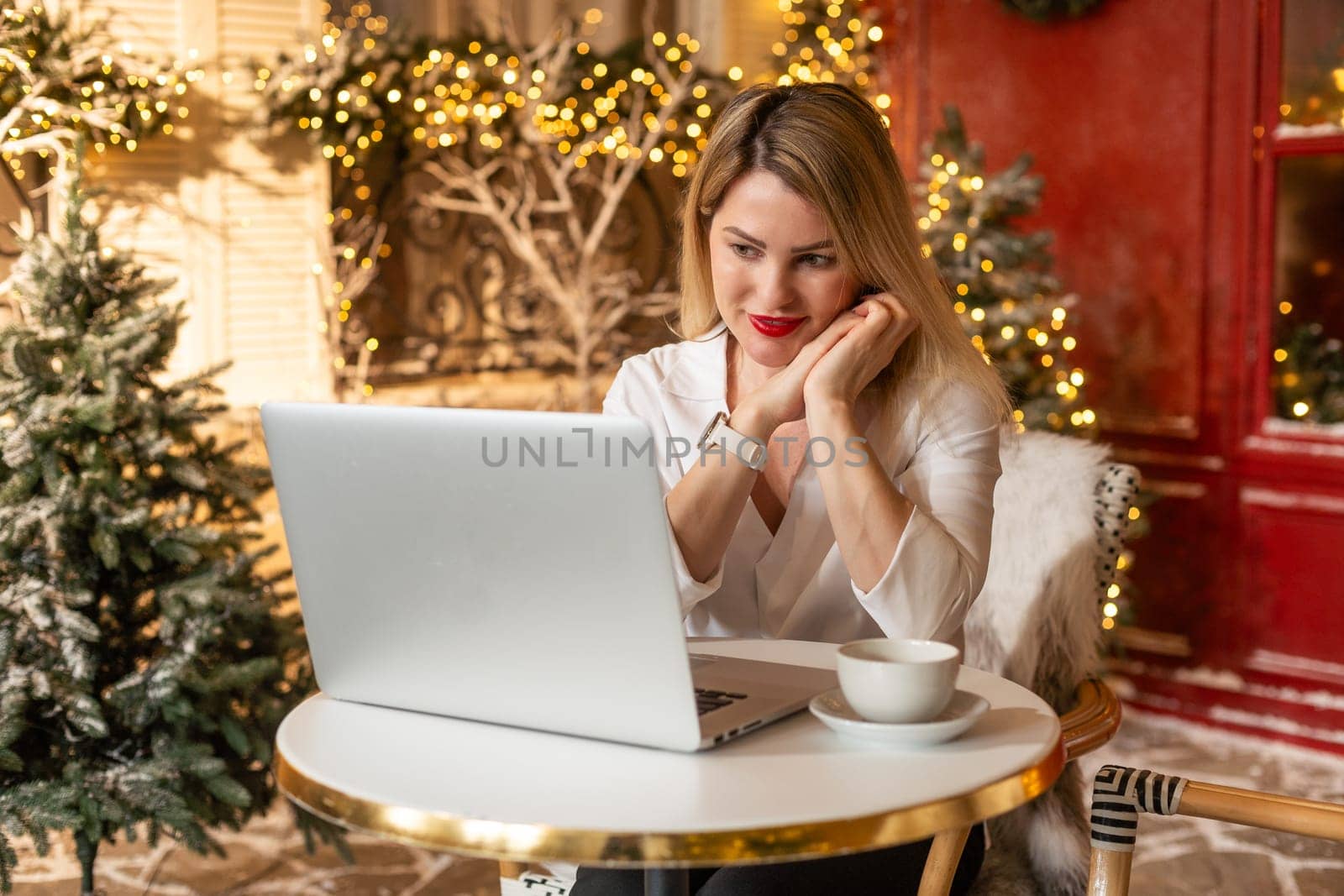 Smiling adult on video call online conference in christmas decorated. Festive young woman talking to friends and family on laptop for seasonal winter celebration. High quality photo