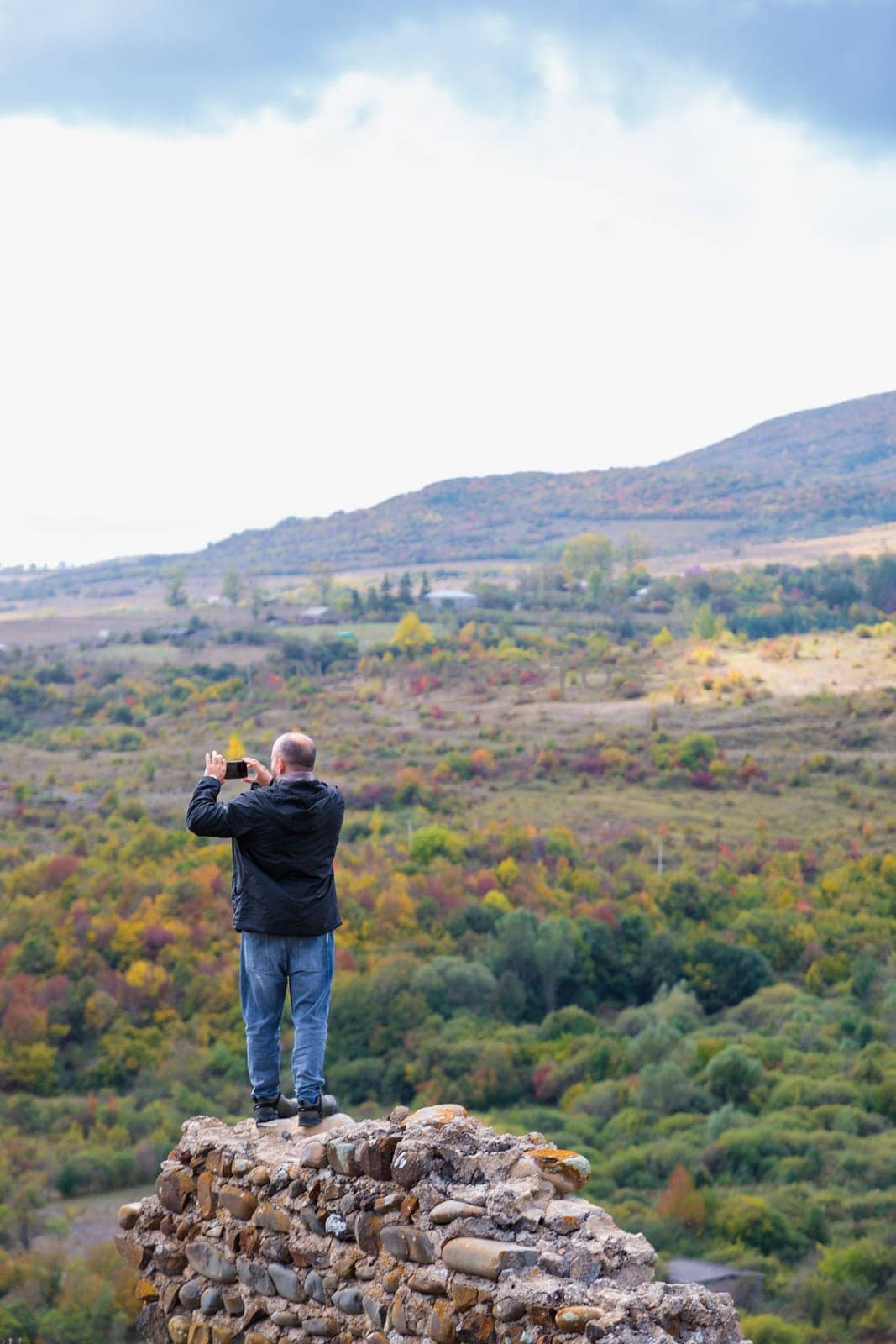 Man taking pictures of mountains from the ruins of the wall by Yurich32
