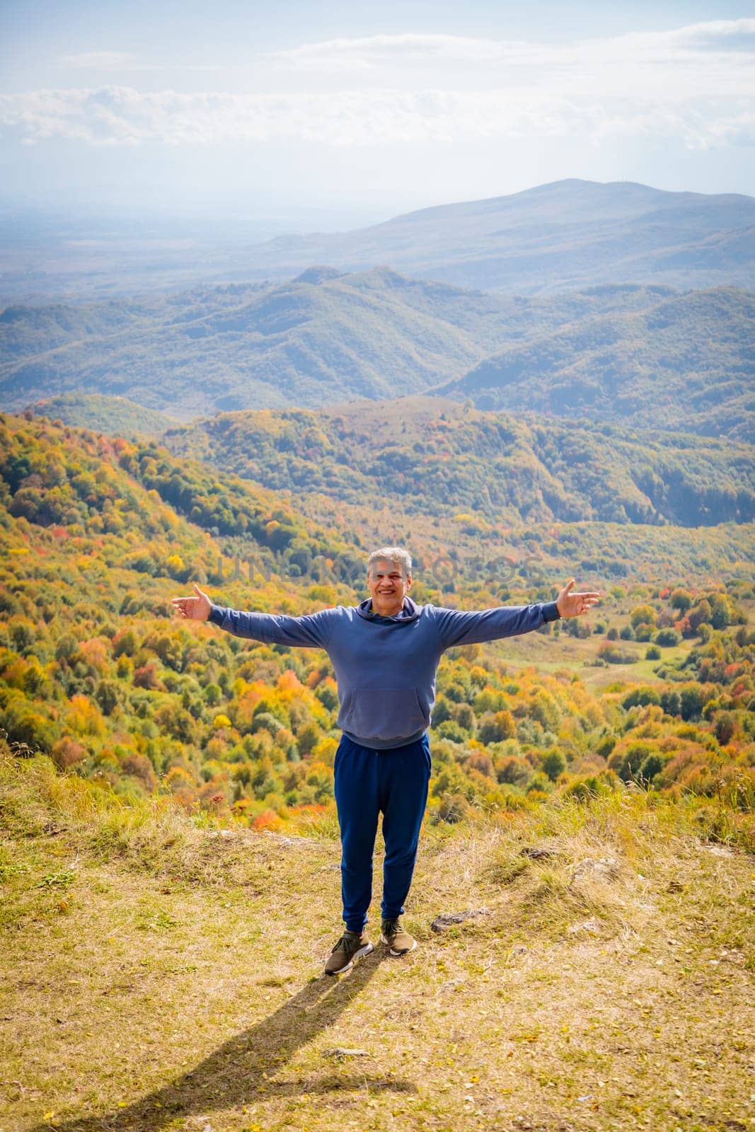 The majesty of the autumn mountains surrounded amazes the man, making him feel the power and tranquility of nature