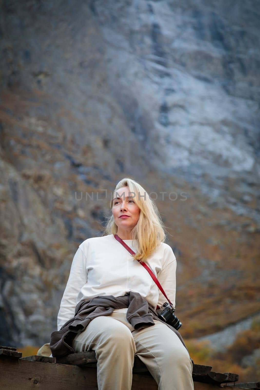 Force of Nature: A girl contemplates the majesty of a waterfall while sitting on a bridge in a mountain