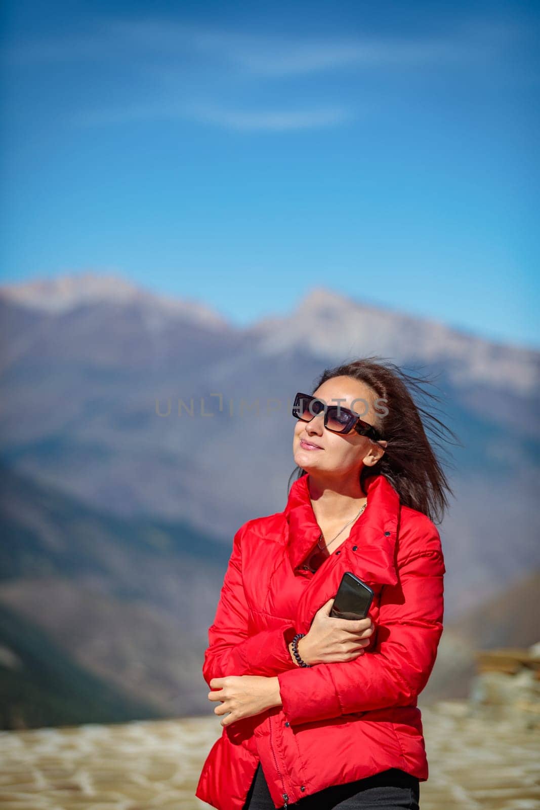 Happy girl taking pictures in the background of snow-capped mountains