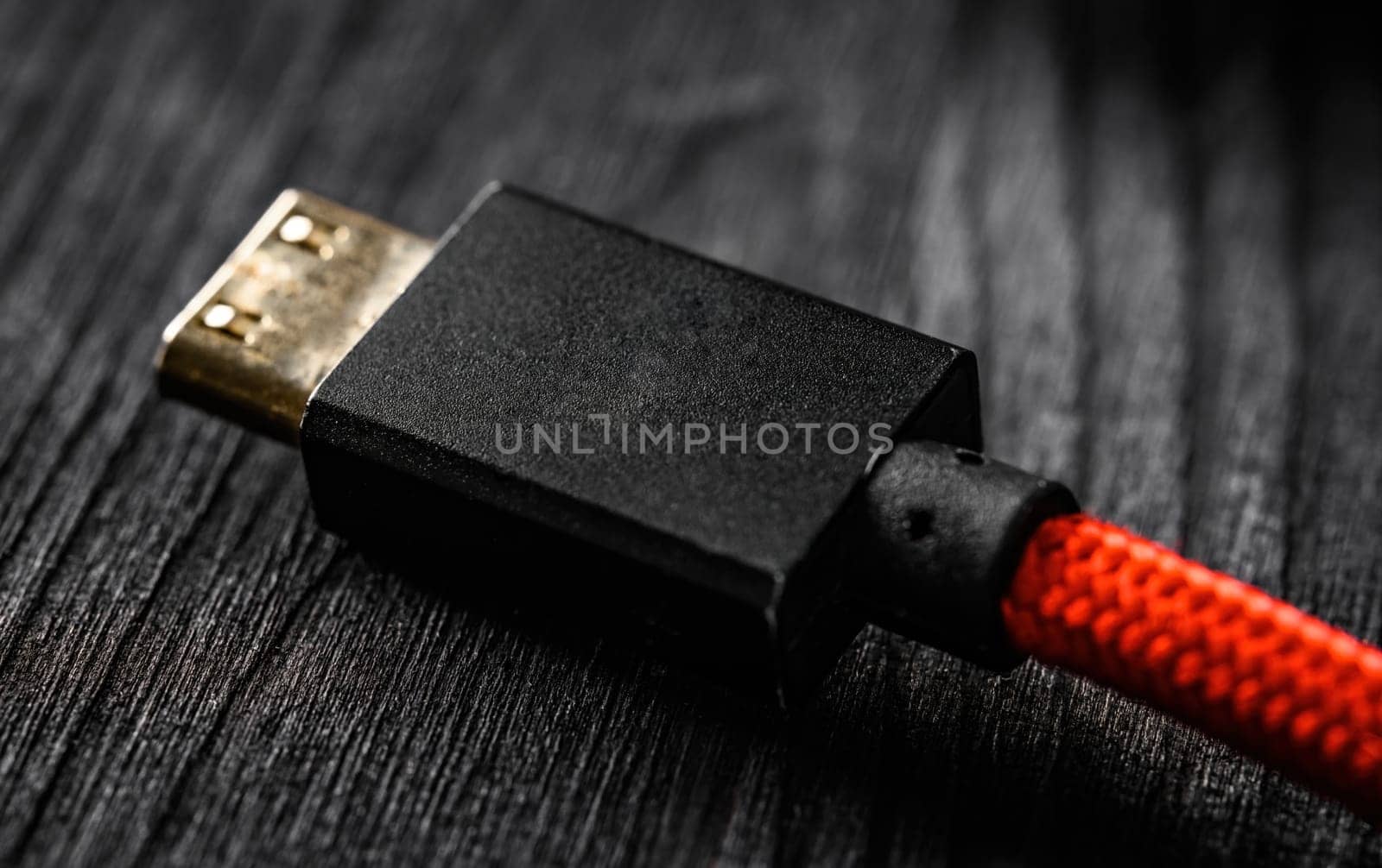 Red wire with HDMI connector, on a dark table, close up view