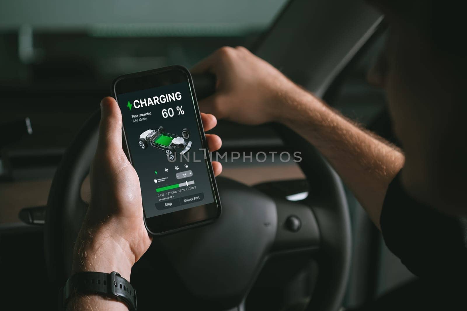 Electric car driver checks battery charging status, range and charging limit on app screen in the car. Smart technology device show EV car recharging data of electric storage in car battery innards.