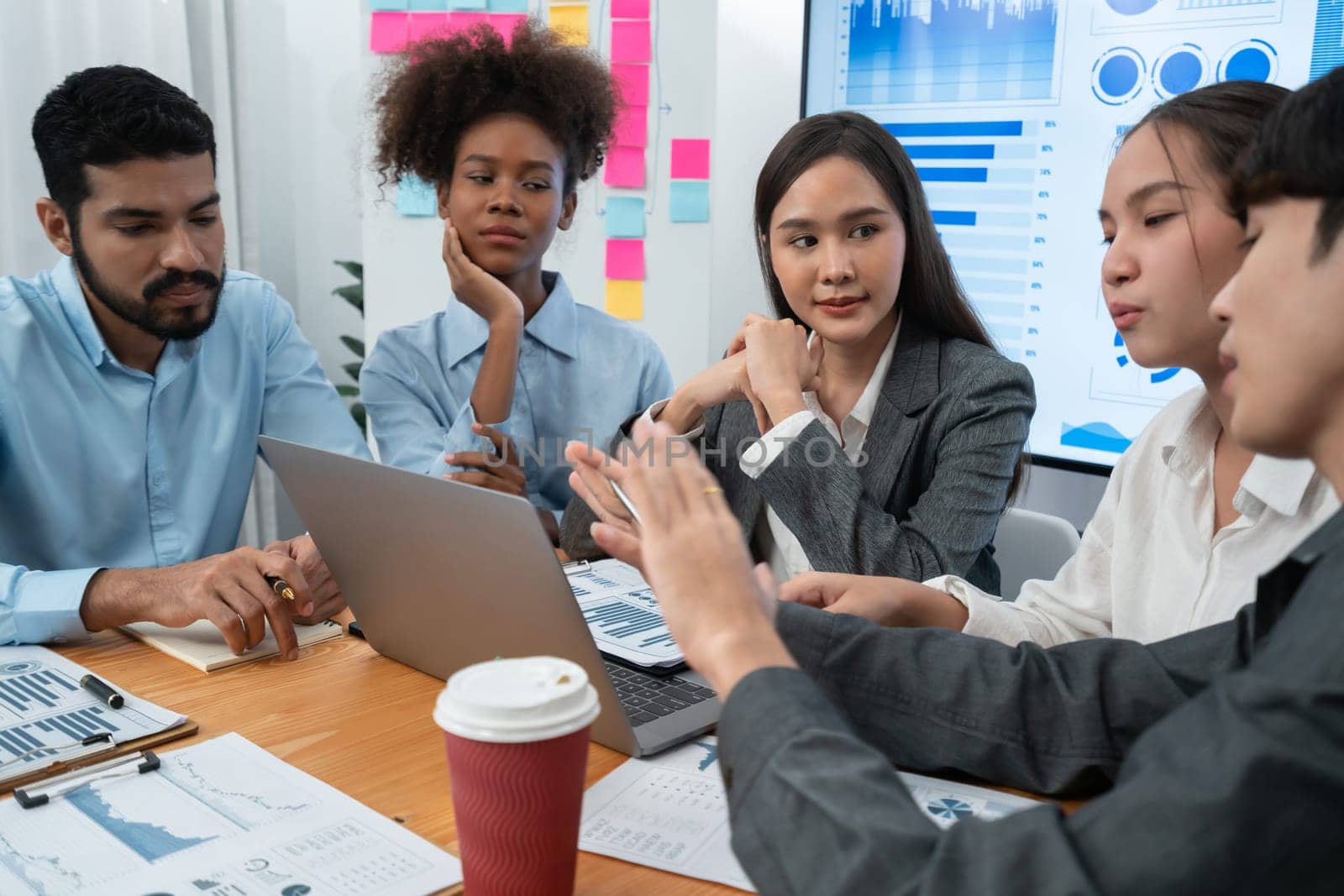 Multiracial analyst team use BI dashboard data to analyze financial report on meeting table. Group of diverse business people utilize data analysis by FIntech for success business marketing. Concord