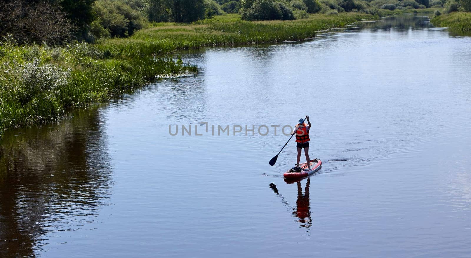 Paddleboarding on lake, aerial view. Stand up paddle boarding (SUP) water sport. Adventure on river on Stand up paddle board. Summer fun, holidays travel on SUP board. Active lifestyle on water.