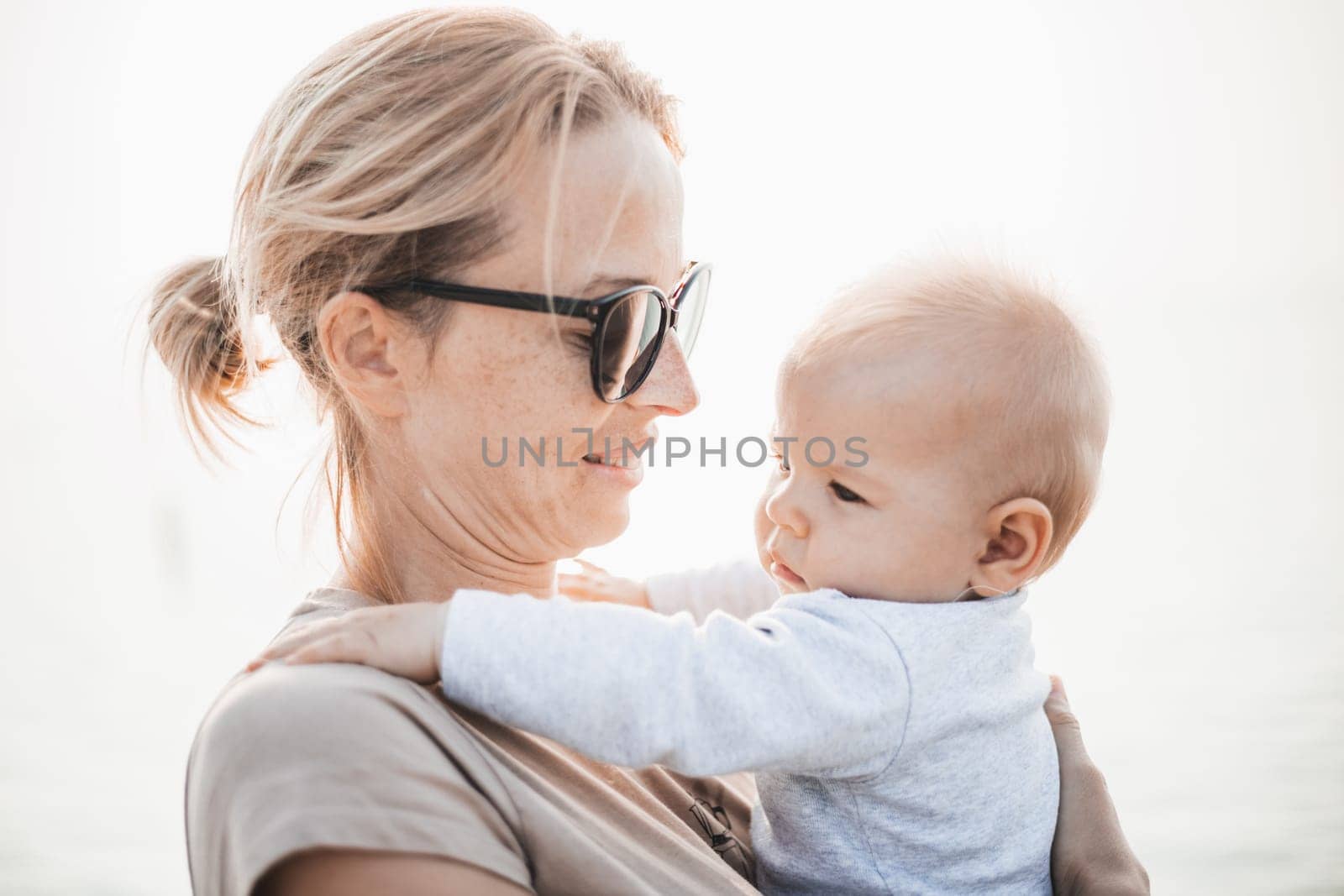 Tender woman caressing her little baby boy infant child outdoors. Mother's unconditional love for her child by kasto