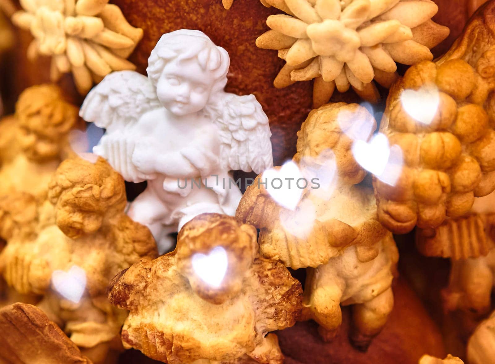 Christmas composition with a figurine of an angel made of sugar on a large pie, surrounded by angels made of dough, close-up. Focus on the foreground.